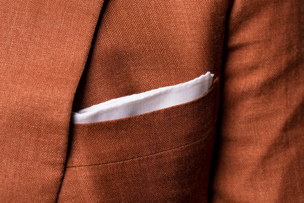 A white pocket square worn on an orange suit