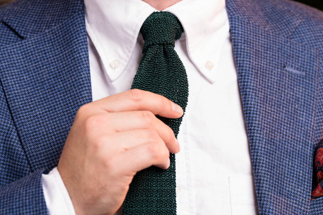 A hand adjust a green knit tie 