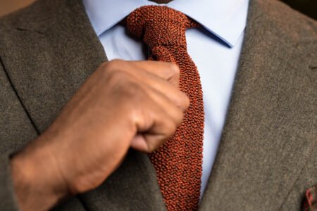 A hand adjust an orange knit tie