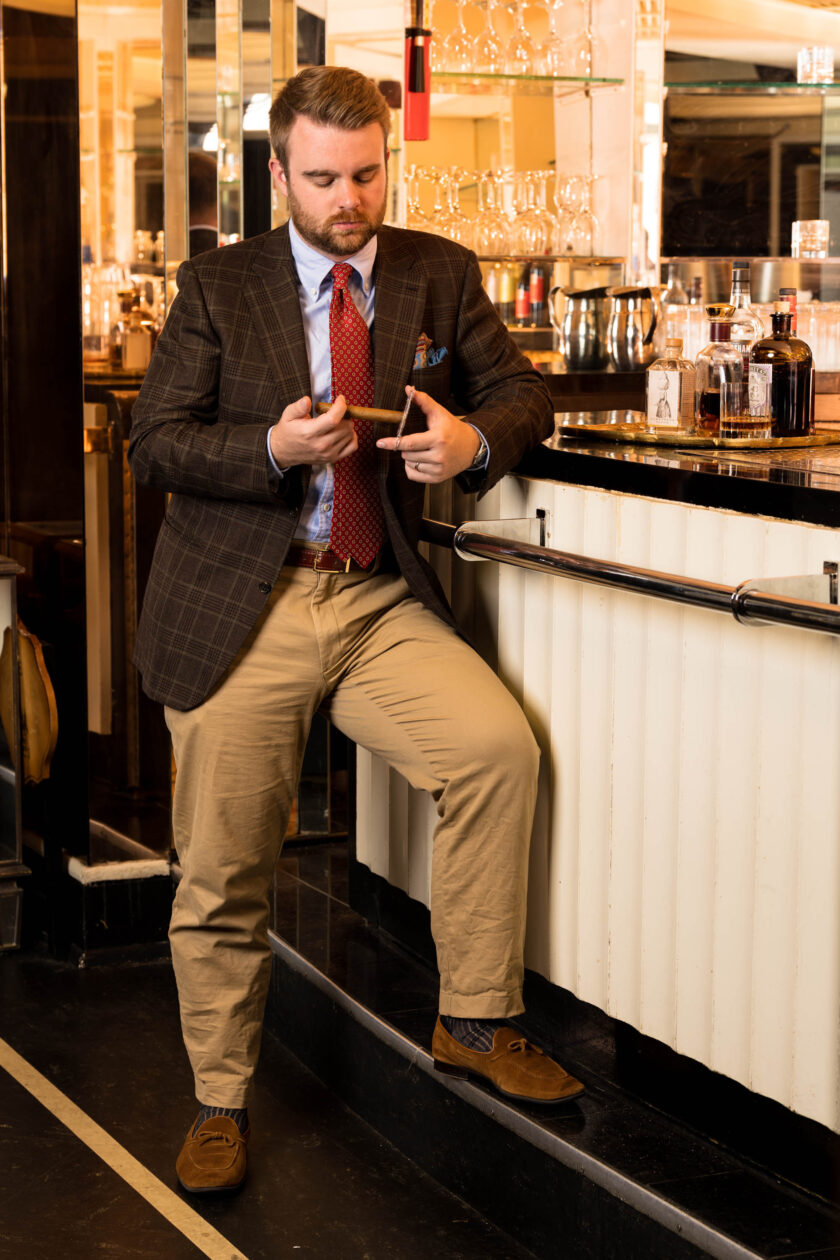 A man leans against a bar in an outfit with many patterns