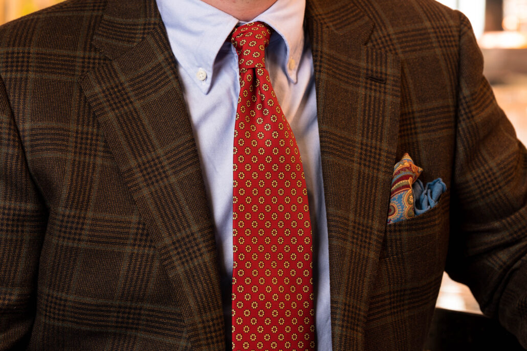 A view of a man's chest wearing a patterned shirt, tie, and pocket square 