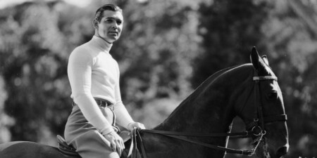 Clark Gable wears a polo neck sweater while riding horseback
