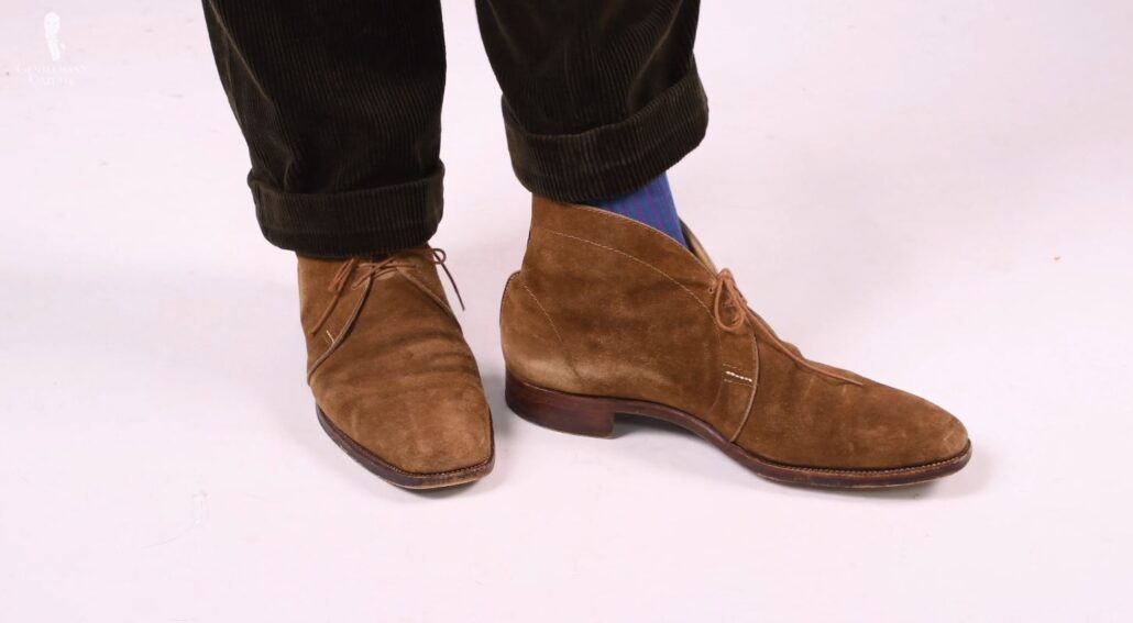 A versatile pair of classic chukka boots in a mid-brown suede and a slim leather sole (Pictured: Teal and Purple Shadow Stripe Ribbed Socks from Fort Belvedere)