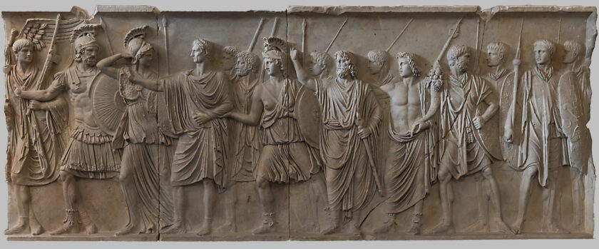 A photograph of a Roman relief carving of figures wearing socks and sandals
