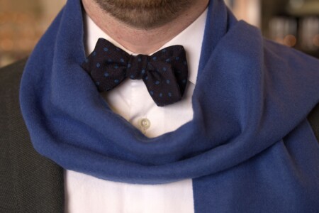The front of a suit worn with a dark blue bow tie and a blue scarf