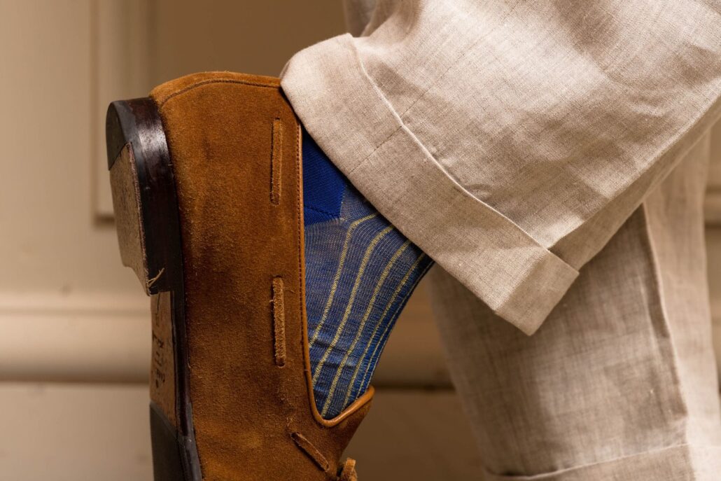 Bright blue socks with yellow stripes worn with brown suede shoes 