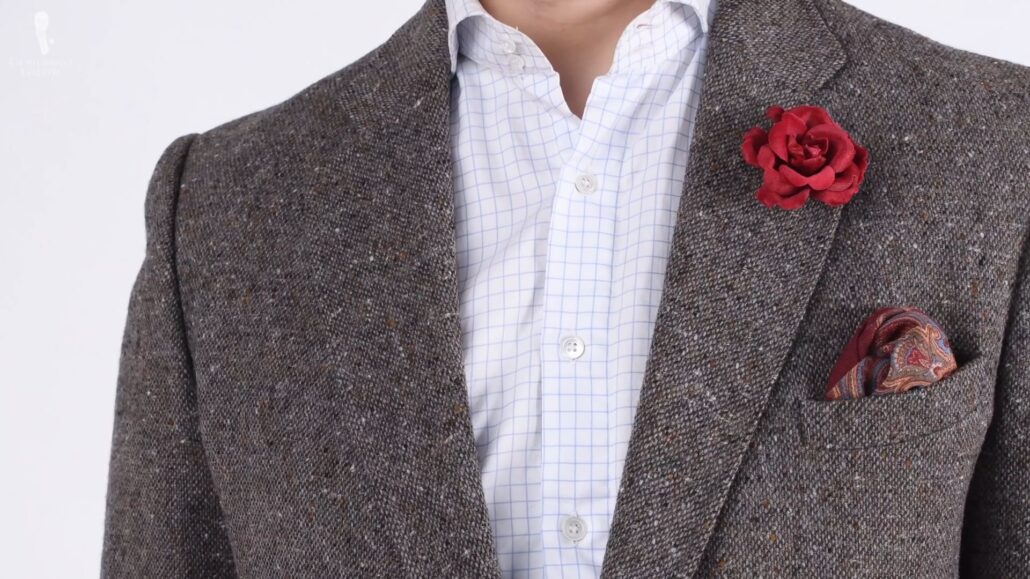 The similar shades of red in the boutonniere and pocket square allow a cohesive look