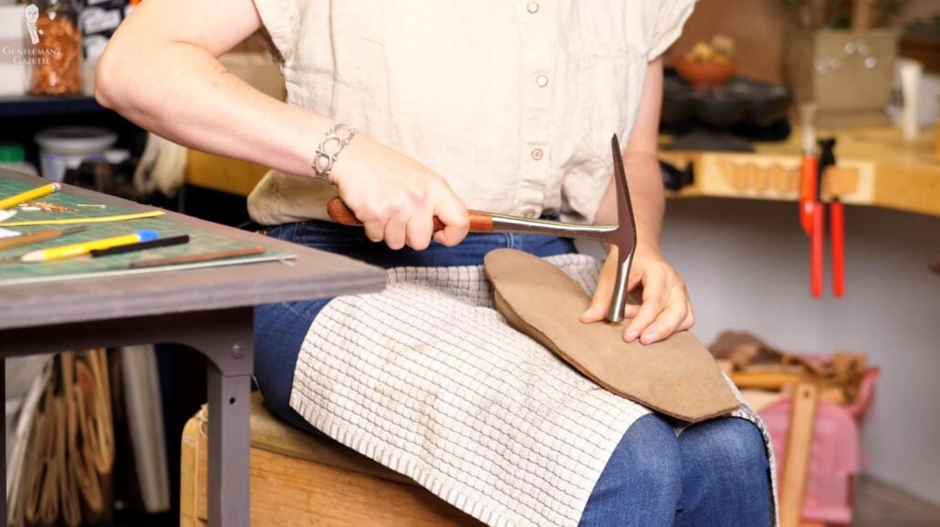 Here, she attaches the insole to the last by tacking