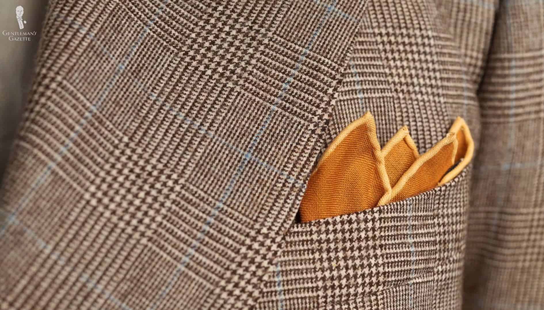 You may opt to show only the edges of a pocket square when paired with a bold-patterned jacket (Pictured: Antique Gold Yellow Silk Wool Pocket Square from Fort Belvedere)