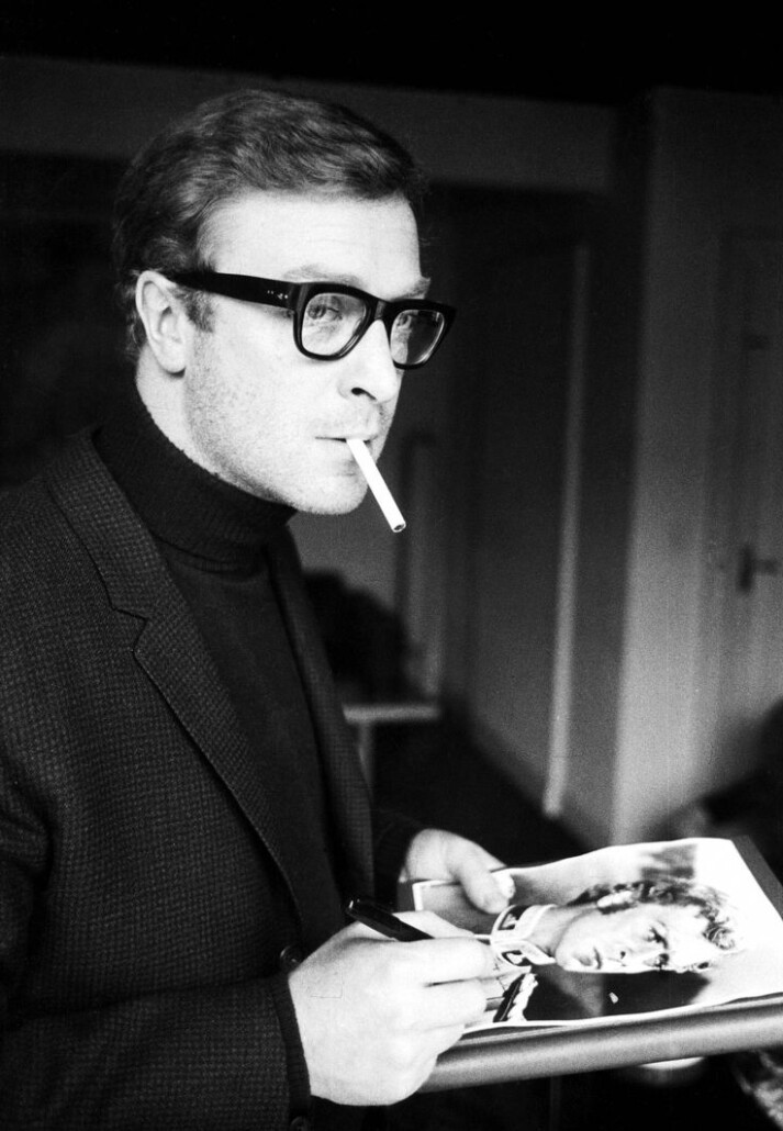 Michael Caine sports a turtleneck sweater while signing an autograph