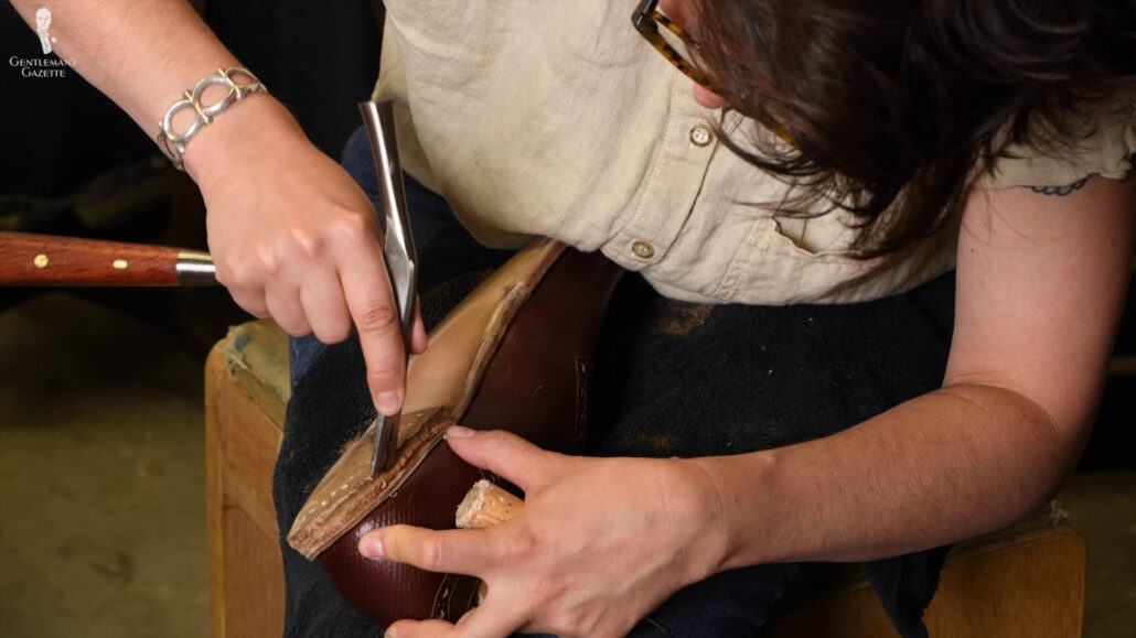 Amara uses a pin hammer to flatten and neaten the edges of the heel layer.