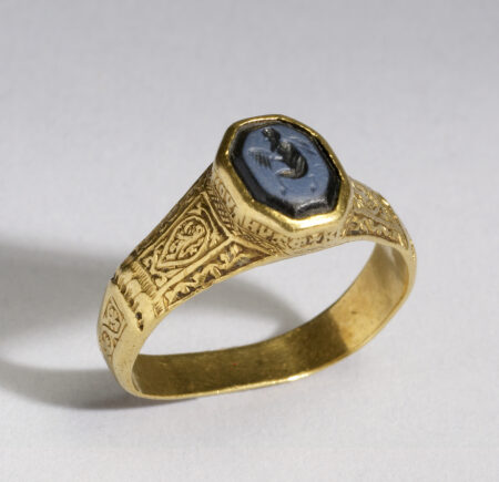 Photograph of a gold signet ring with a dark stone face