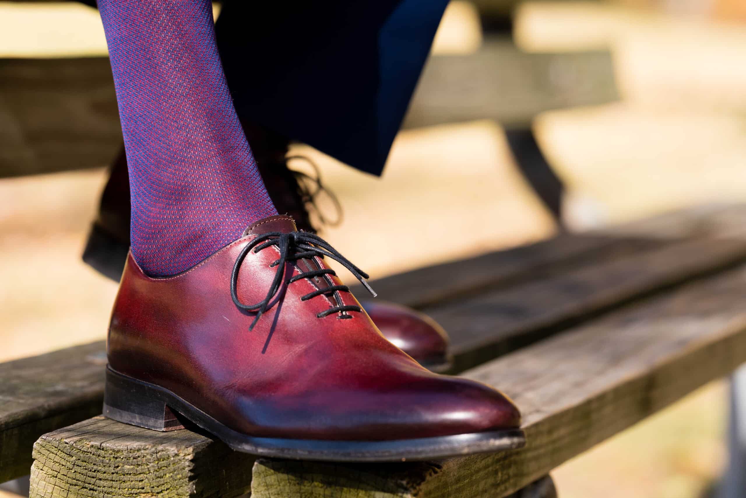 A photo of oxblood shoes with blue and red socks