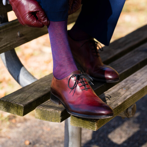 Oxblood shoes and blue and red socks on a bench in the fall