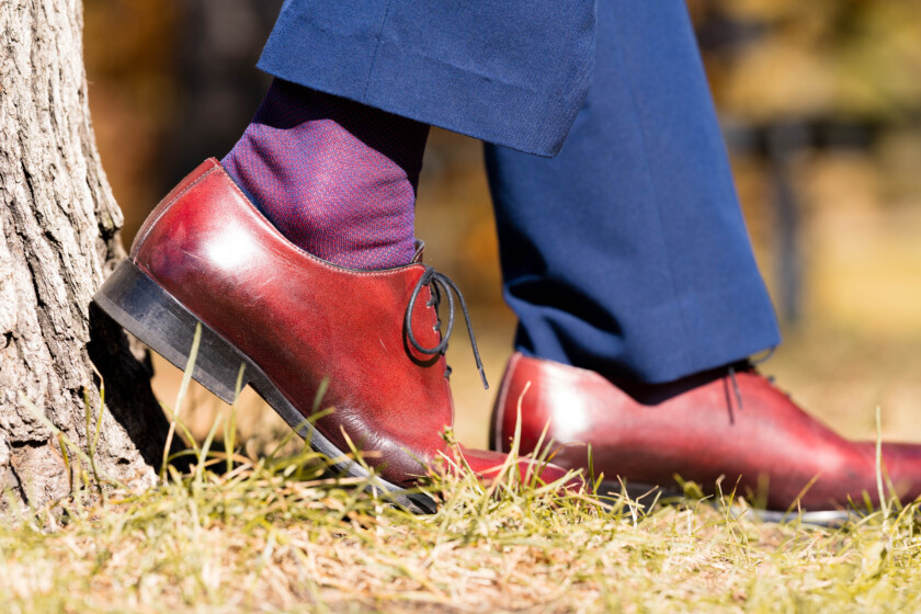 Photo of an oxblood pair of shoes worn with blue trousers and blue and red socks