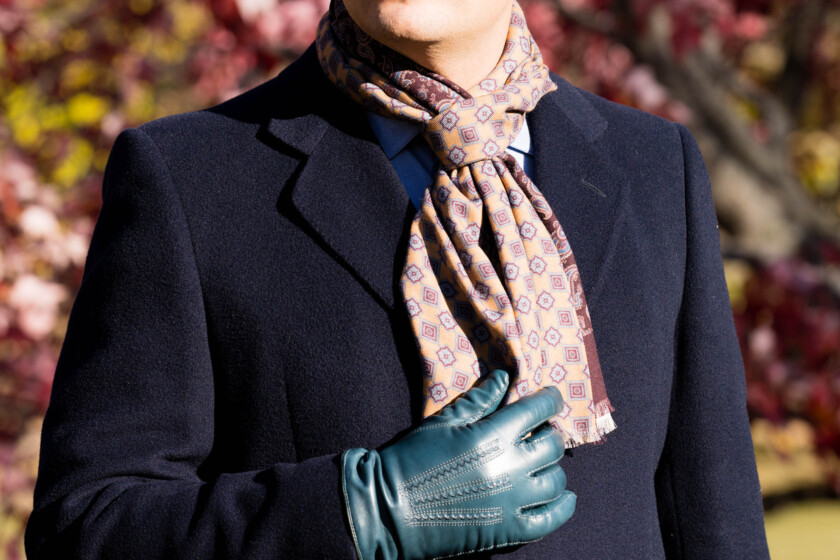 Detail of a knotted scarf worn with a navy overcoat