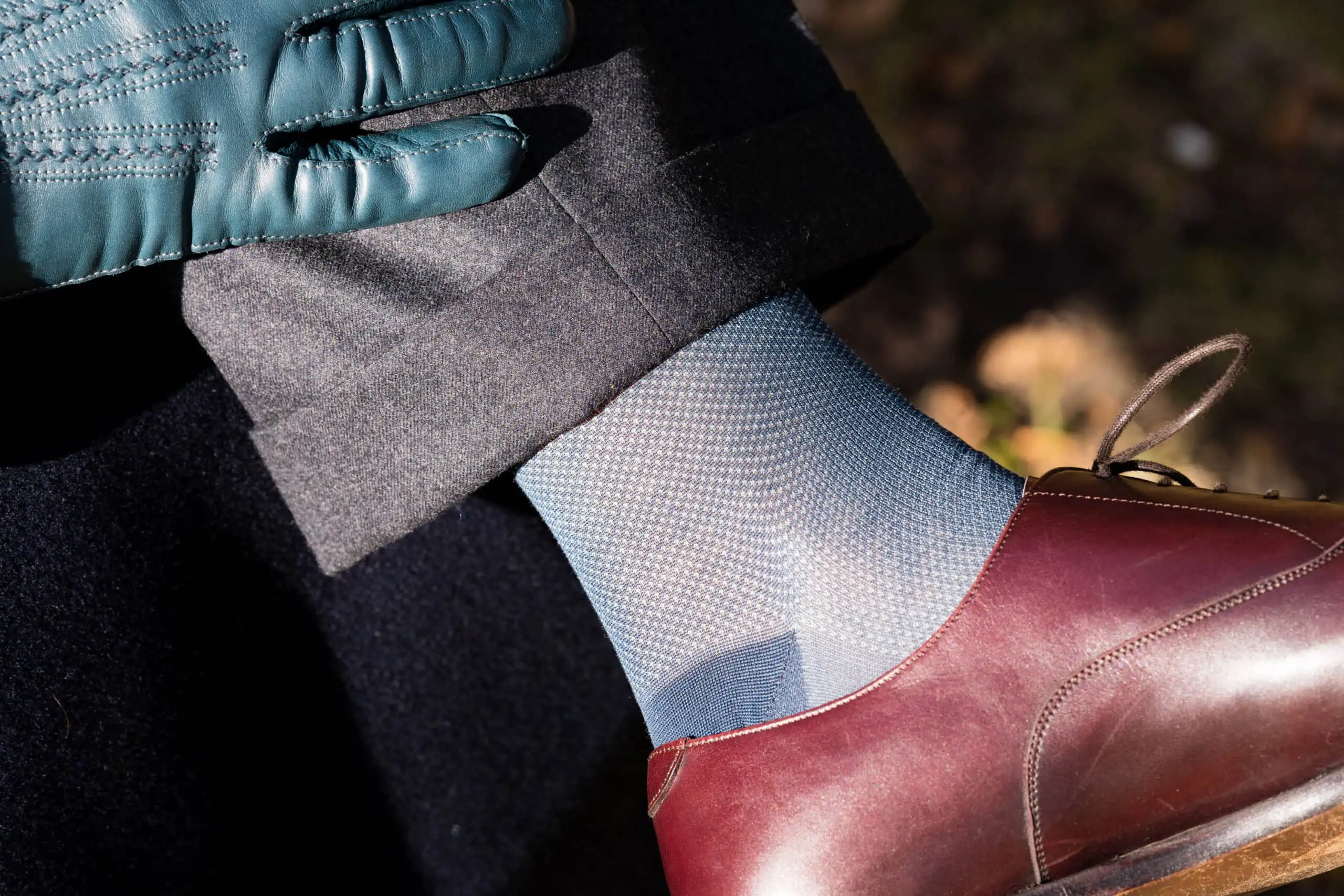 A photograph of oxblood shoes with blue socks and blue gloves