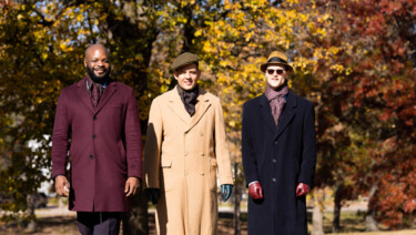 Three men walk through a park in the fall
