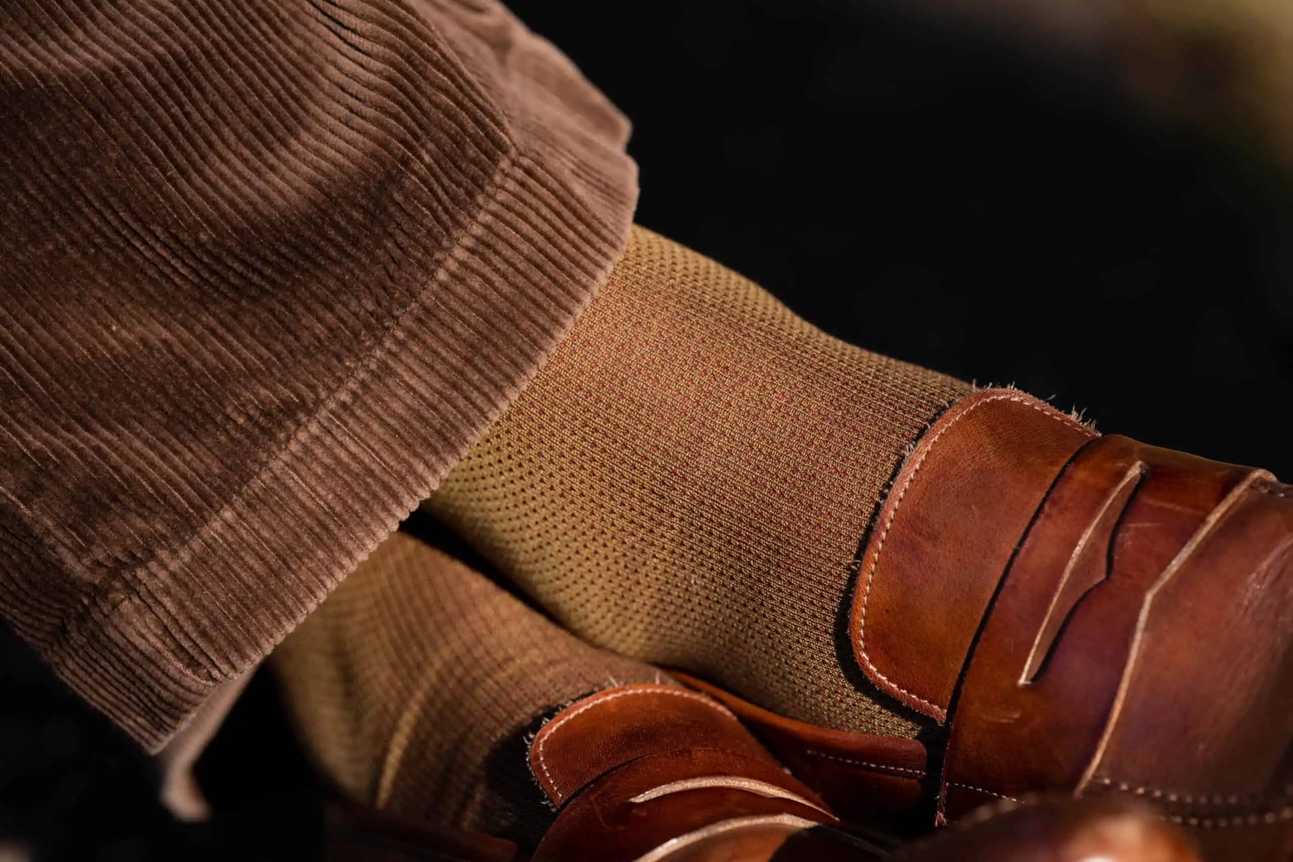 A close up photo of brown loafers worn with khaki and red socks