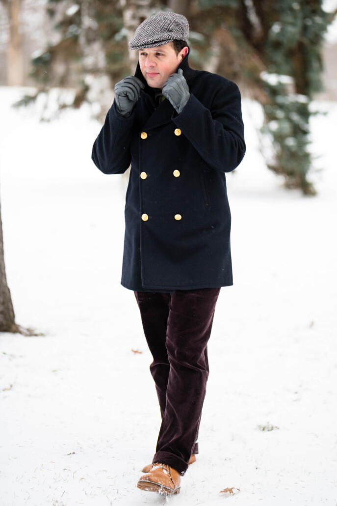 Raphael walks in the snow in a navy pea coat with Fort Belvedere accessories