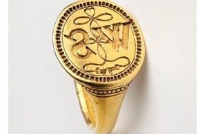 A photograph of a gold signet ring with the letters WS
