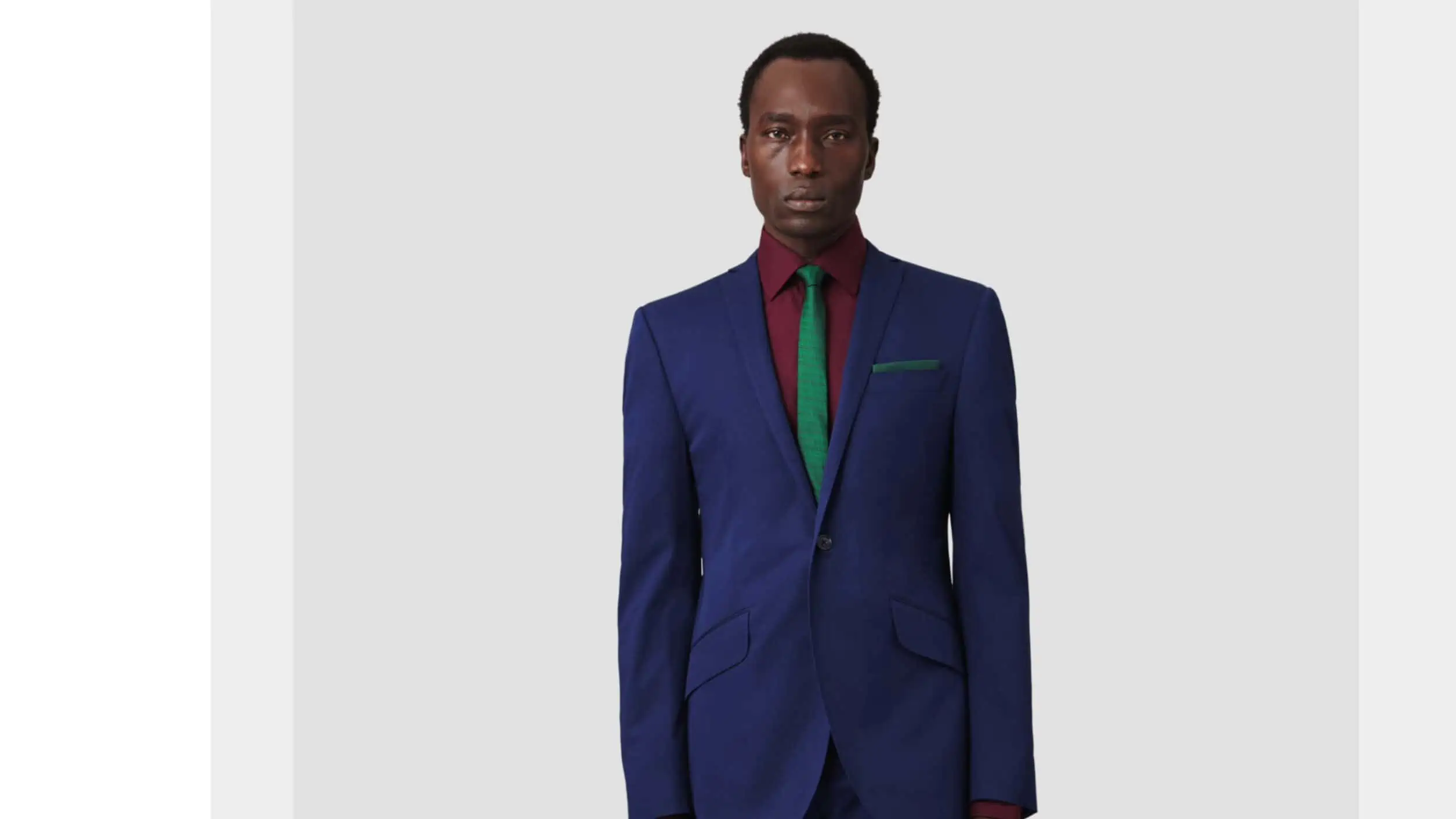 Bespoke style in a suit with the color coordination of a blue suit, green necktie and red dress shirt.