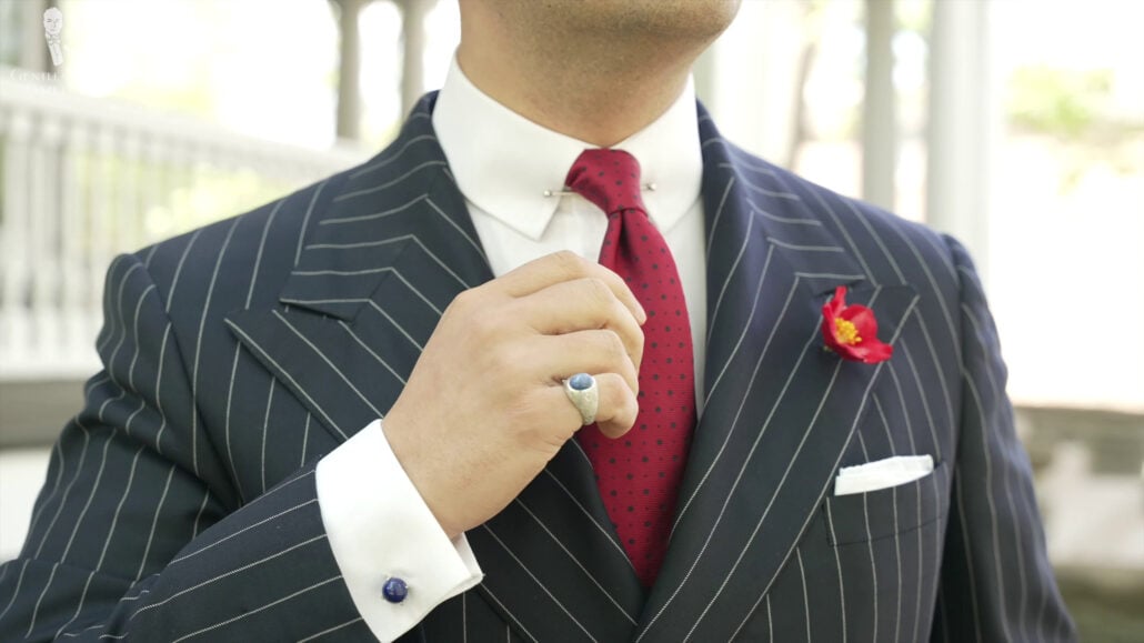 Raphael is in a formal chalk stripe black suit, red and black polka dot tie, and red boutonniere. Red Christmas Rose Boutonniere Buttonhole Flower Fort Belvedere