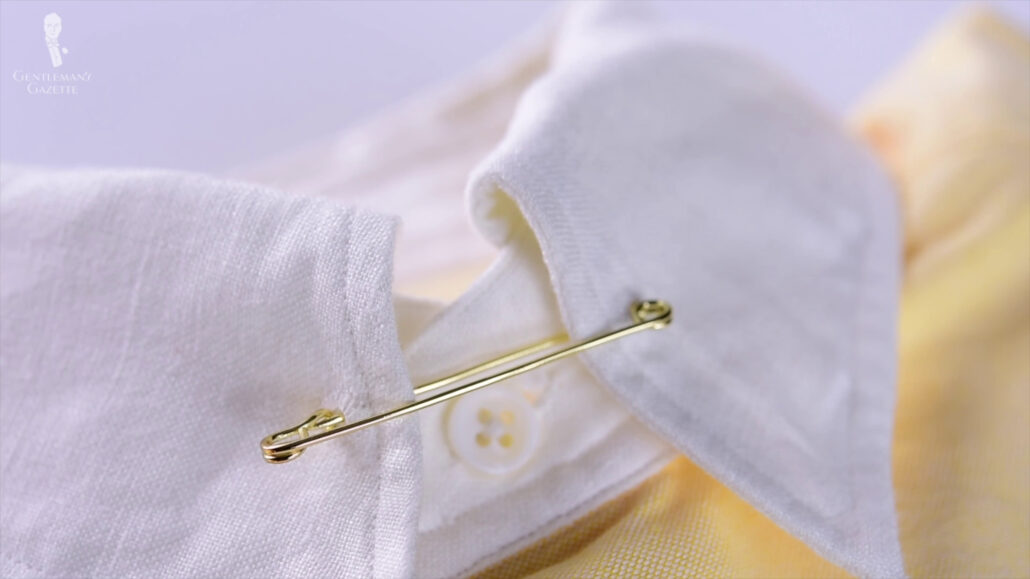 A gold collar pin holds the two ends of a dress shirt together.