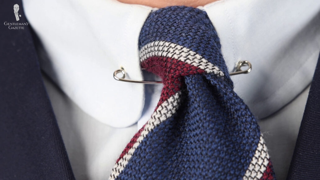 A piece of men's jewelry that passes underneath the knot of a necktie.