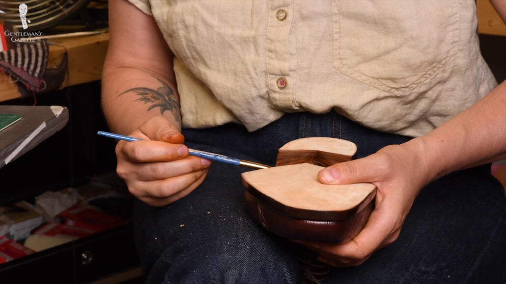 After ensuring the proper width and slant of the paintbrush, Amara starts dyeing the shoe.