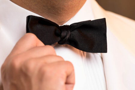 Photo of hand adjusting black bow tie