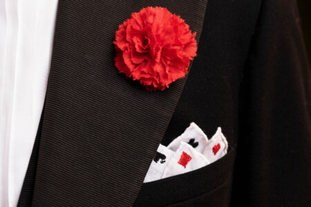 Close up photo of a red carnation in a button hole and a pocket square
