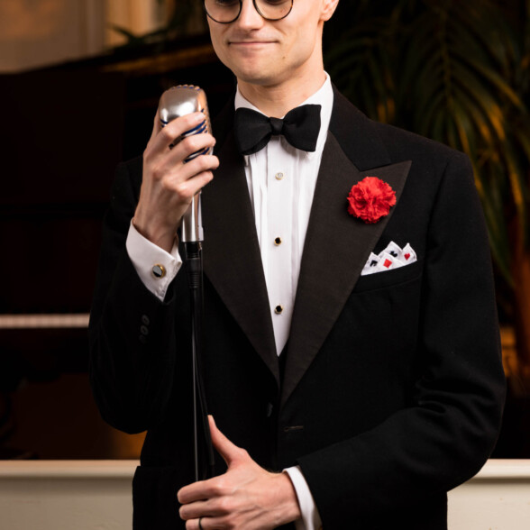 Photo of Preston in Black Tie standing near a microphone