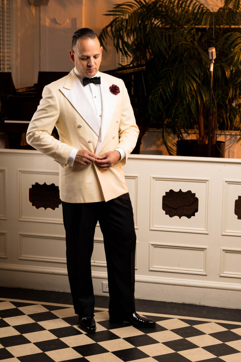 Photo of Raphael standing in an ivory dinner jacket