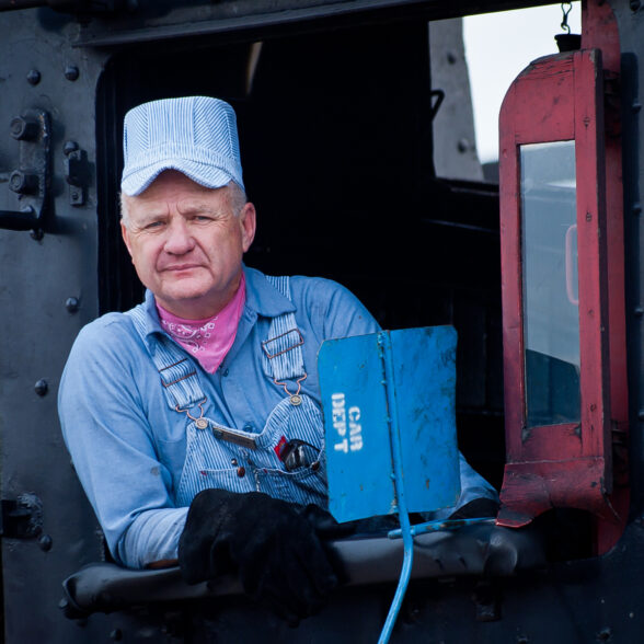 Photo of a Steam Locomotive Engineer wearing seersucker cap and overalls
