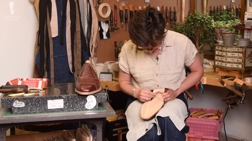 Amara glass smoothing the sole of a leather shoe.
