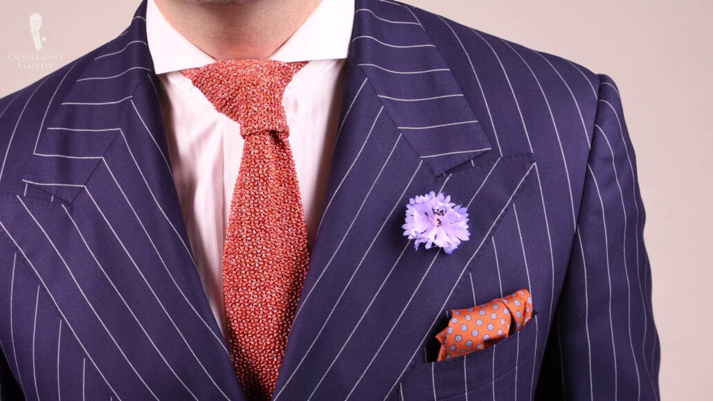 The Navy blue suit pairs well with the accent of an orange tie.