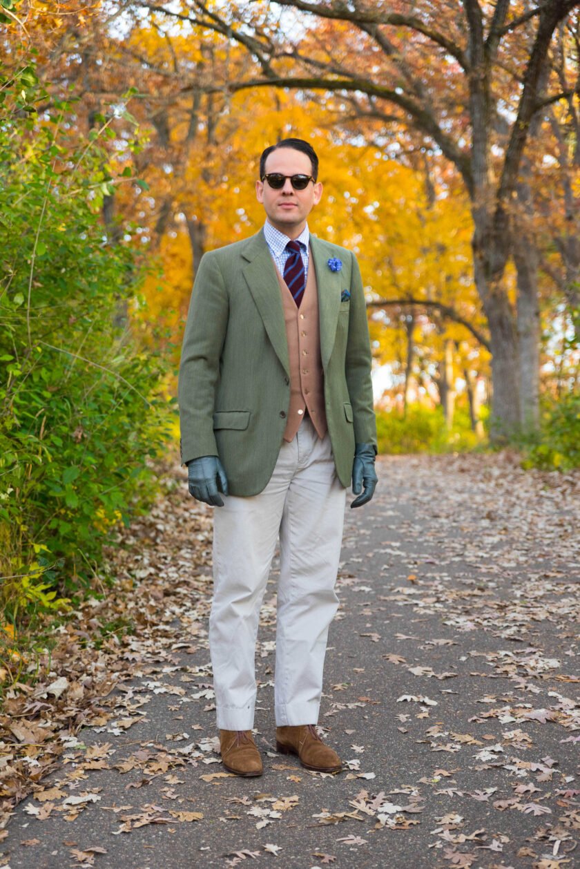 Photo of Raphael wearing Atelier sunglasses Diagonal stripe tie white blue check shirt olive green coat Blue Cornflower Boutonniere cream pants tan vest green gloves