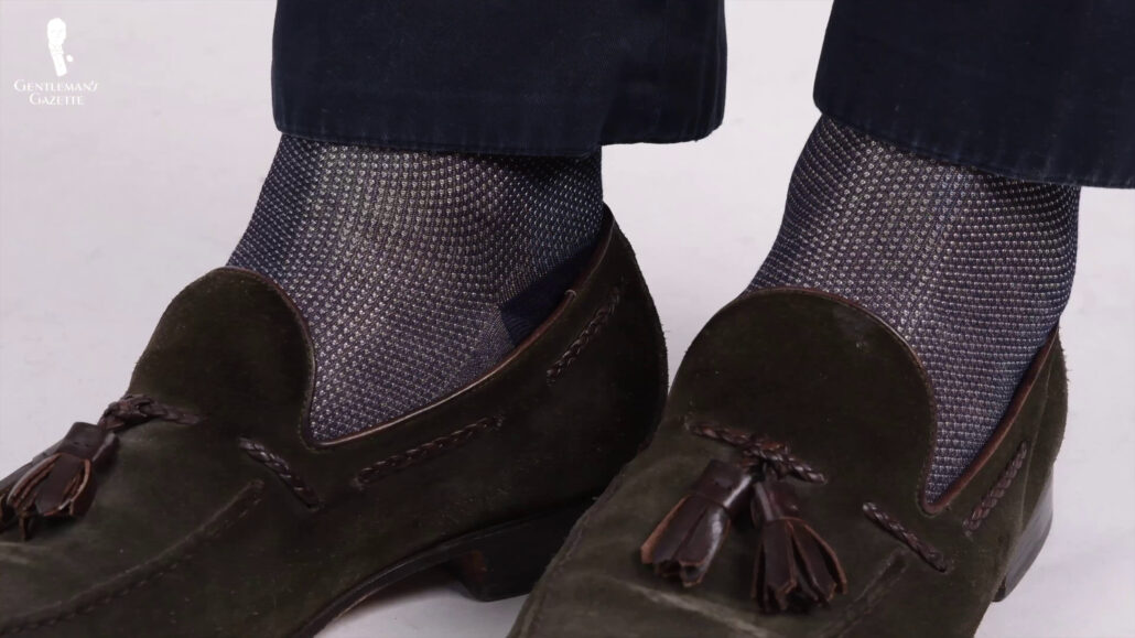 Wearing a navy blue and two toned socks that coordinates with the green loafers.