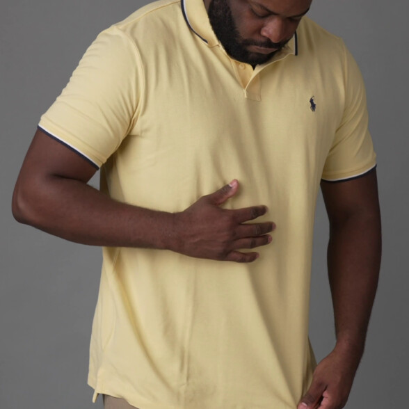 Kyle assessing a yellow Ralph Lauren polo with his hand.