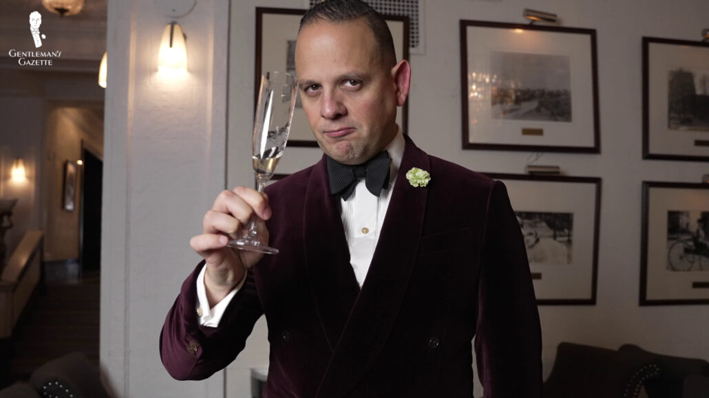 Raphael holding a champagne glass while wearing formal wear