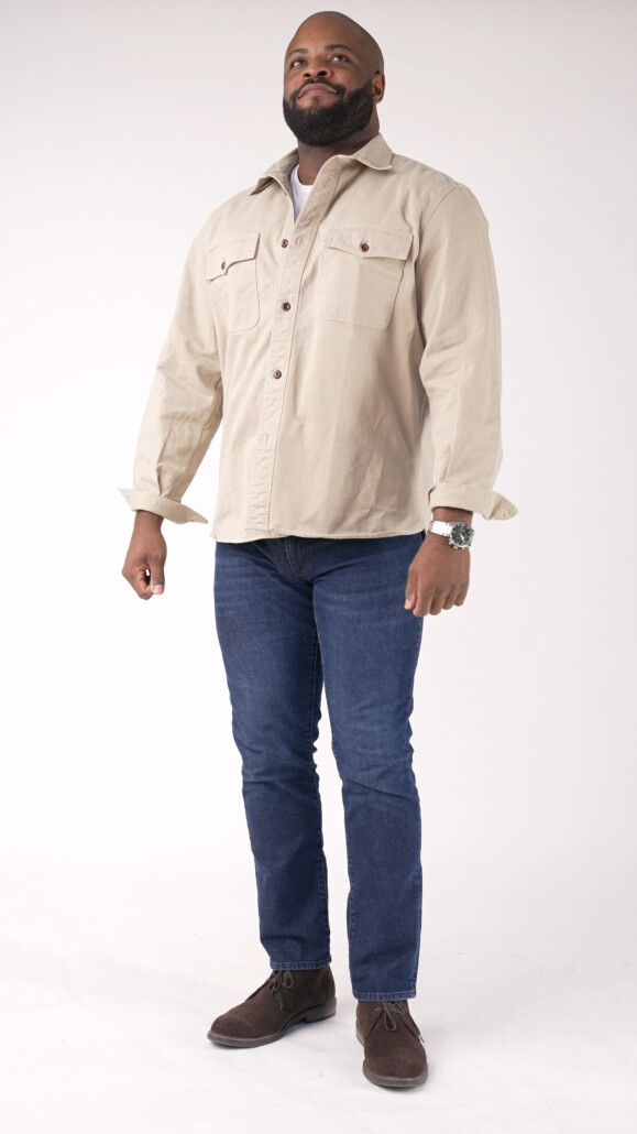 Photo of Kyle wearing a khaki overshirt, denim jeans, and dark brown suede chukka boots