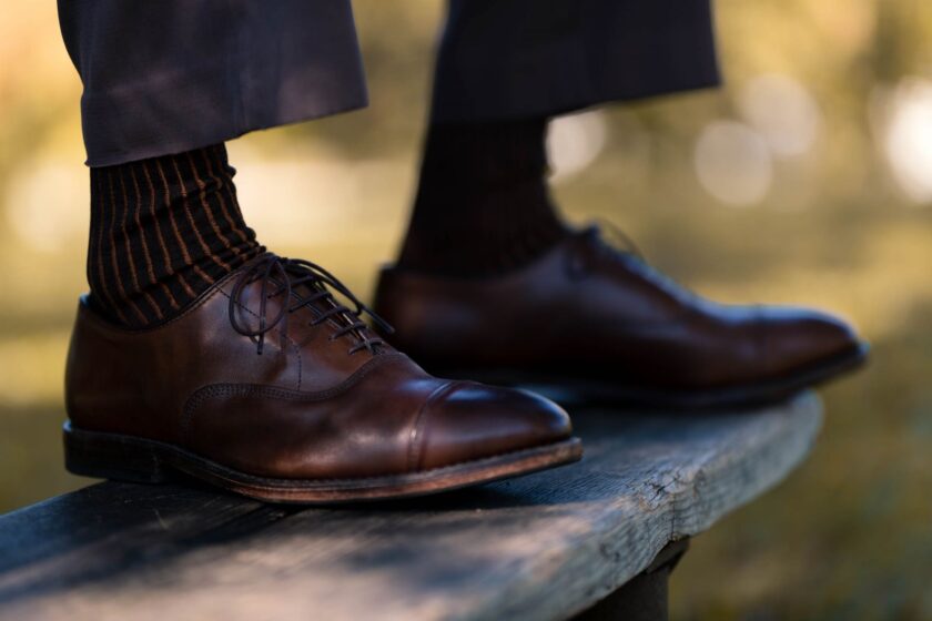 Photo of orange and charcoal striped Fort Belvedere socks worn with charcoal trousers