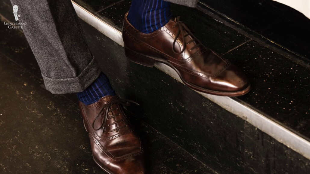 Dark gray cuffed trousers combined with a brown oxford shoes and shadow striped shocks in dark navy and royal blue from Fort Belvedere.