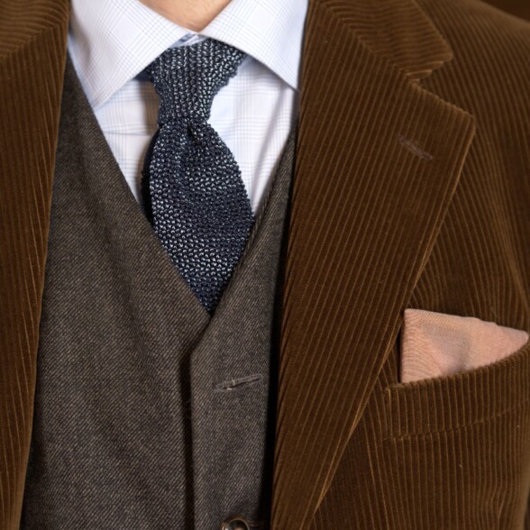 Photo of Corduroy jacket worn with silk knit tie gray waistcoat earthone pocket square details shot