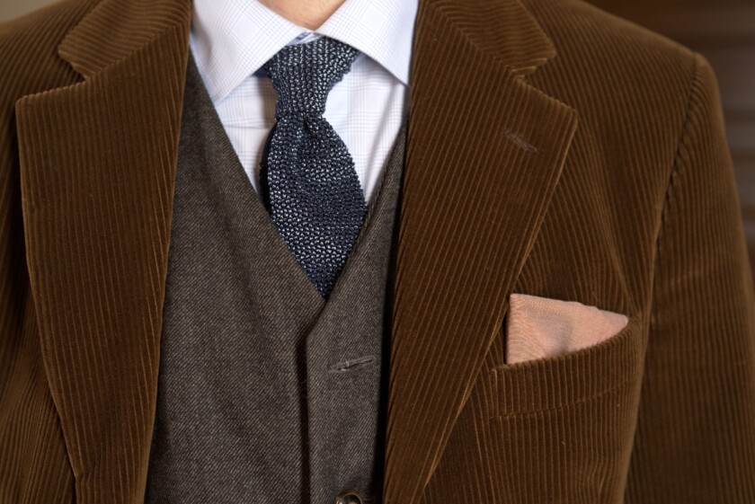 Photo of Corduroy jacket worn with silk knit tie gray waistcoat earthone pocket square details shot