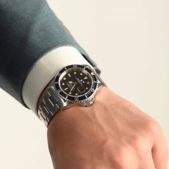 a man wearing a diver's watch with a suit