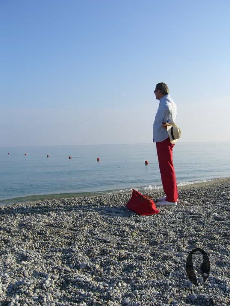 Photo of Figure on beach in sneakers nantucket red trousers dress shirt panama hat sunglasses