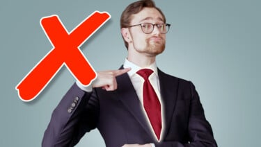 Wearing a suit, Preston points to the novelty knot of his tie
