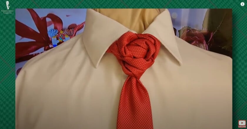 a red tie with a rose bloom knot over a white dress shirt with a spread collar